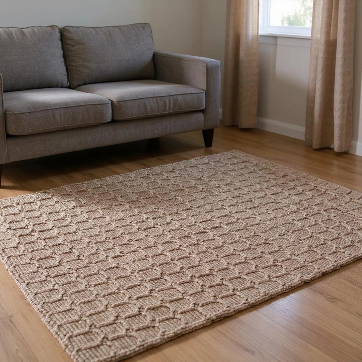 Living room with a gray sofa and a textured beige jute rug on wooden flooring.