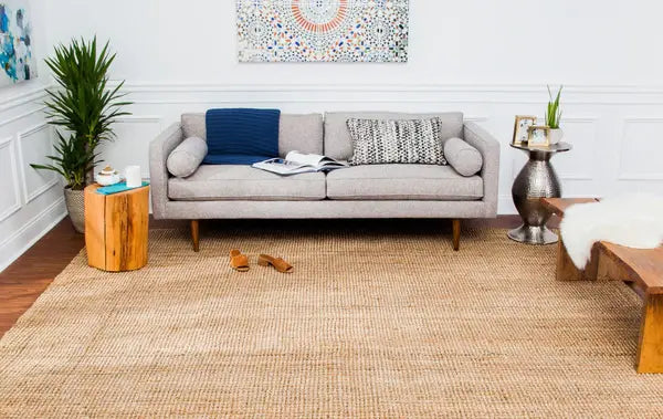 Living room with a gray sofa, wooden coffee table, decorative items and natural jute rug.