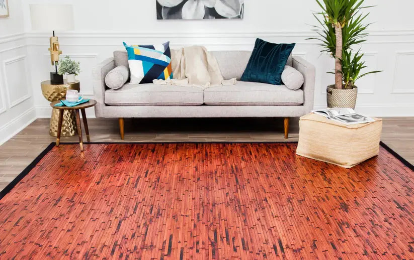 Living room with a wooden floor, white sofa, and mahogany bamboo rug