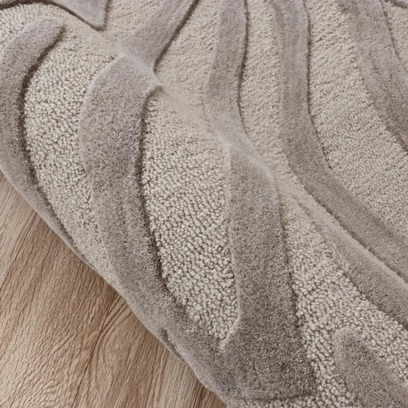 Close-up of a textured taupe wool rug on a wooden floor