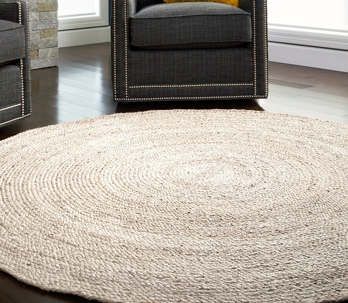 round ivory jute rug on wood floor with dark chairs
