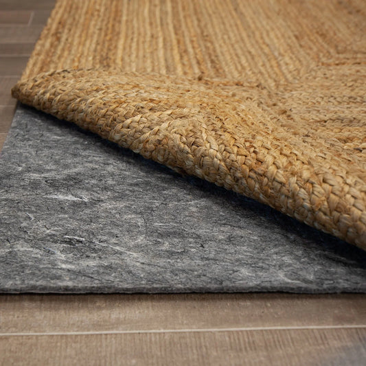 a gray felted rug pad revealed beneath a rolled back corner of a jute rug 