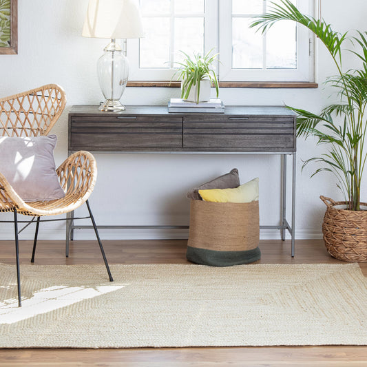 a wicker chair, credenza and potted plant in a space with a light handmade natural jute rug 