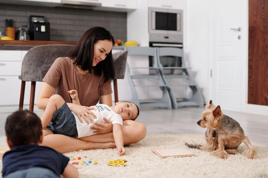mom with two kids and small dog playing on rug 