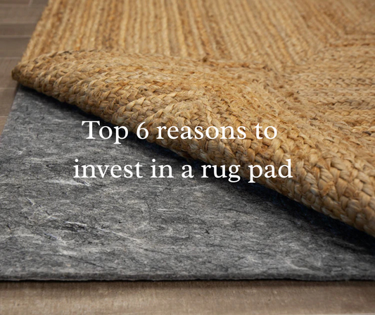 a close-up of  the corner of a natural jute area rug curled to reveal a rug pad and the title Top 6 reasons to invest in a rug pad