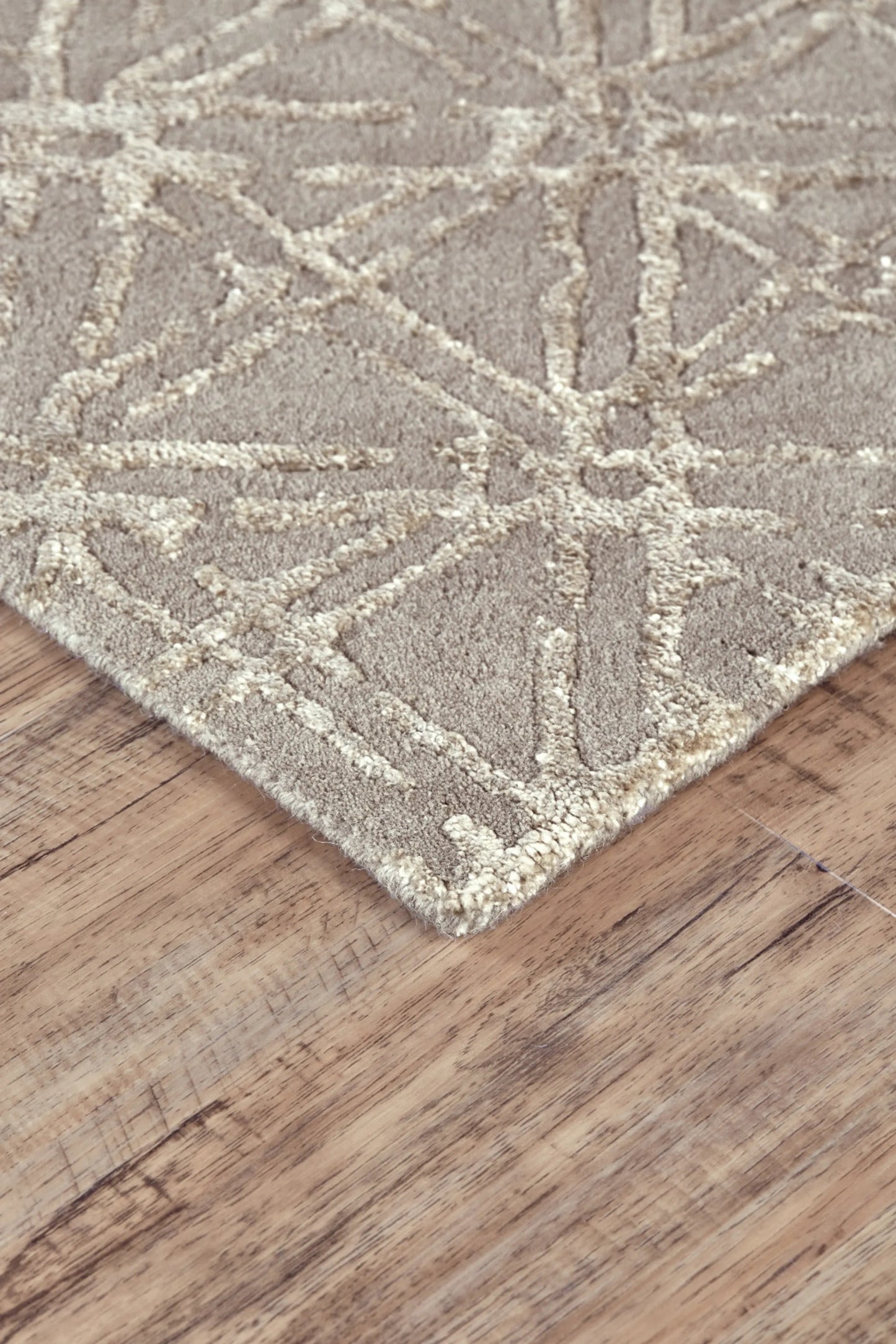 Close-up of a textured wool rug with geometric pattern on a wooden floor