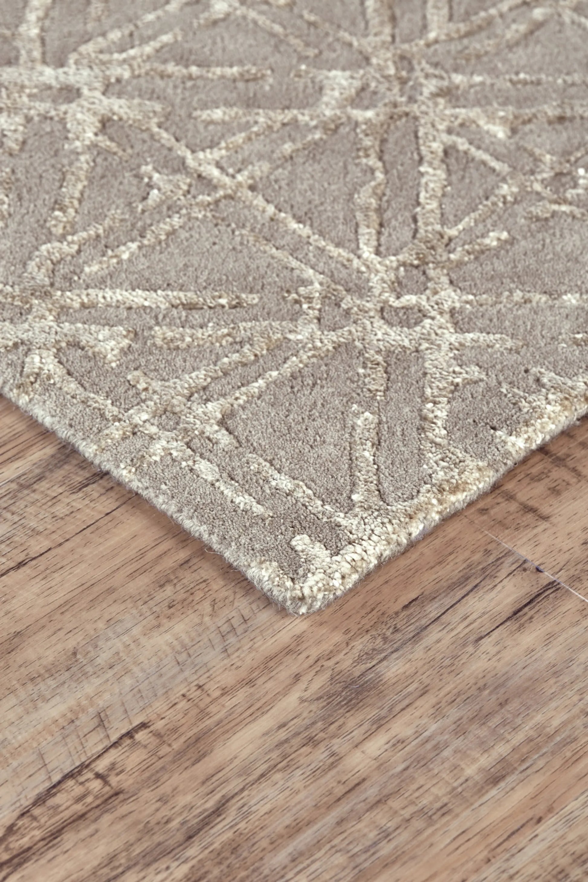 Close-up of a textured wool rug with geometric pattern on a wooden floor