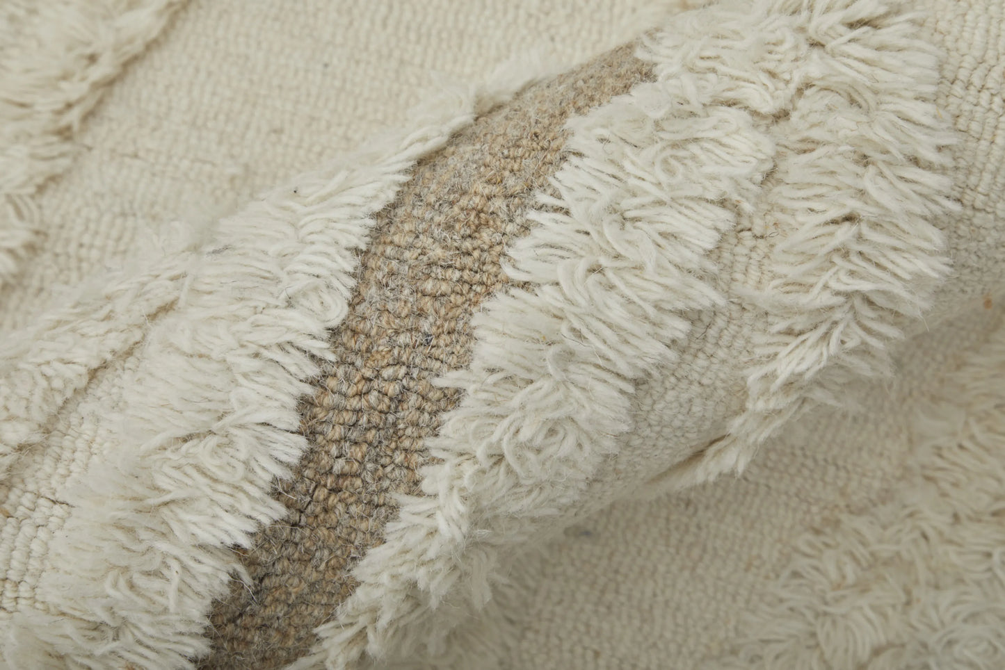 Close-up of textured fabric with fringes in beige and brown tones.