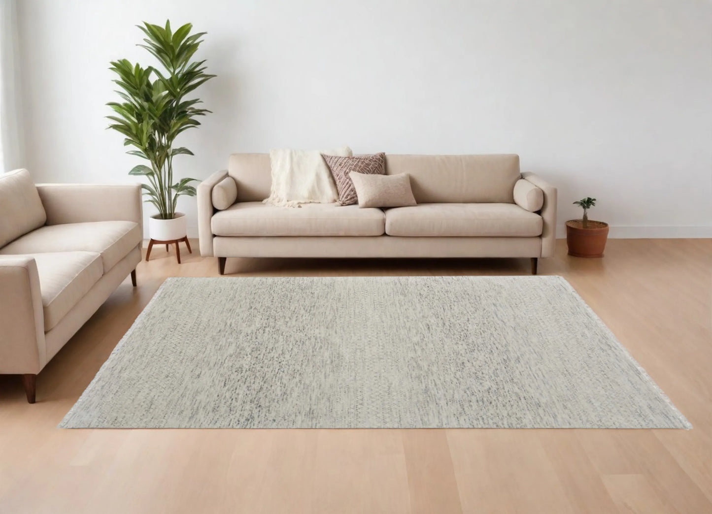 Living room with a beige sofa, gray wool rug, and decorative plants on a light wood floor.