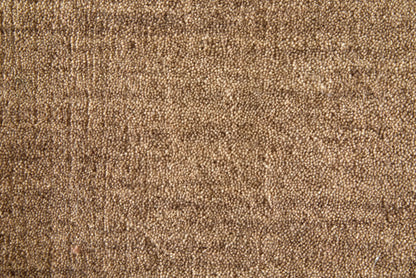 A close-up texture shot of a brown woven fabric or carpet material, showing a detailed, granular surface pattern.