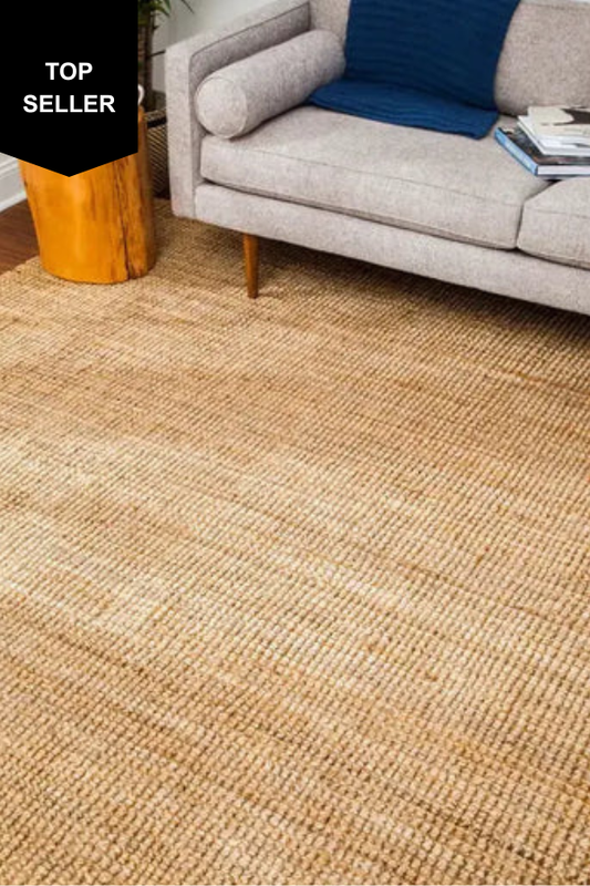 jute rug in a living room with a gray sofa and blue pillow.