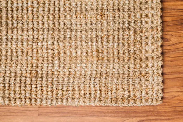 corner of a natural jute rugl on a wooden floor
