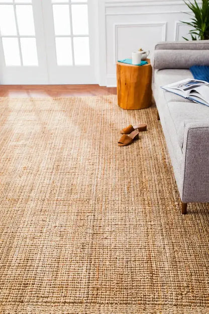 Living room with a natural jute rug, gray sofa, and wooden side table.