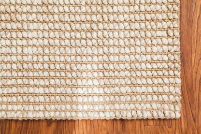 corner of woven ivory and beige rug on wood floor
