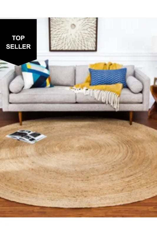 Round woven jute rug in front of a gray sofa with colorful pillows in a living room setting.