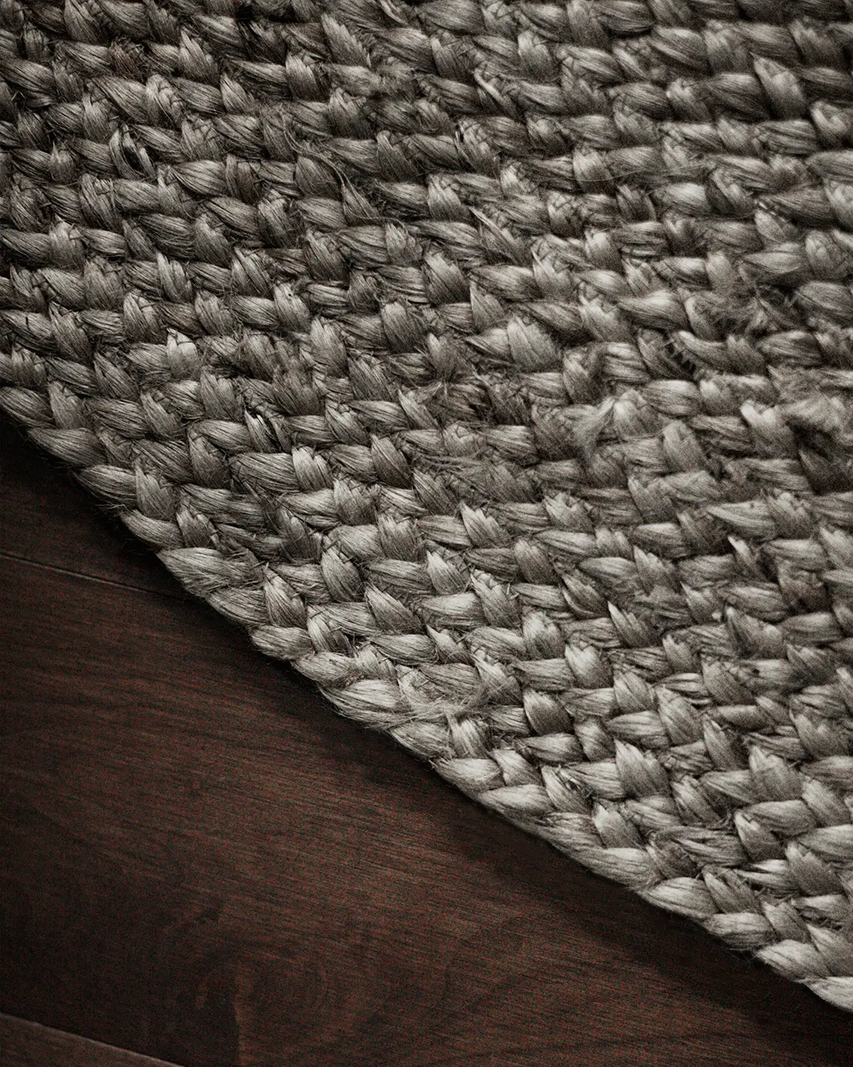 Close-up of a textured round gray woven jute rug on a wooden floor