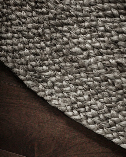 Close-up of a textured round gray woven jute rug on a wooden floor