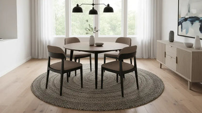 Dining room with round table and chairs on a round gray jute rug, large windows, and modern decor.