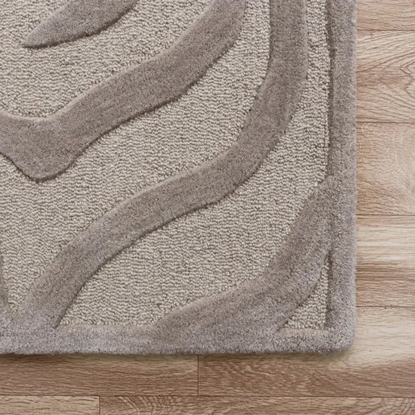 Close-up of a textured  taupe wool rug on a wooden floor