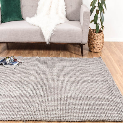 Andes Handloom Woven Gray Jute Area Rug in front of couch