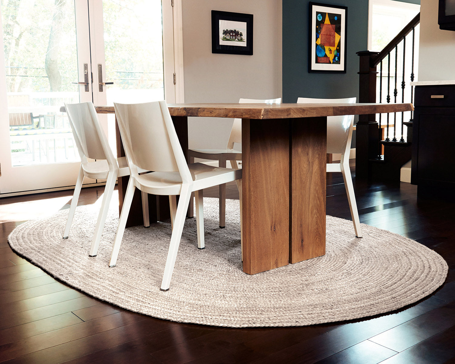 wooden table and white chairs on oval ivory jute rug
